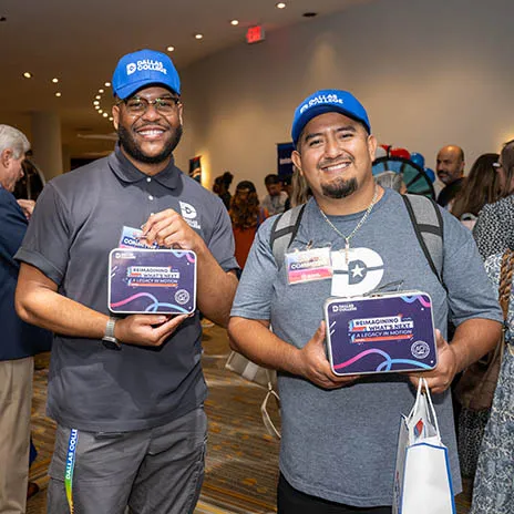 Two Dallas College employees pose with commemorative lunch boxes.