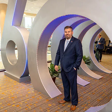 Dr. Justin Lonon, Dallas College Chancellor poses with 60th Anniversary sculpture.