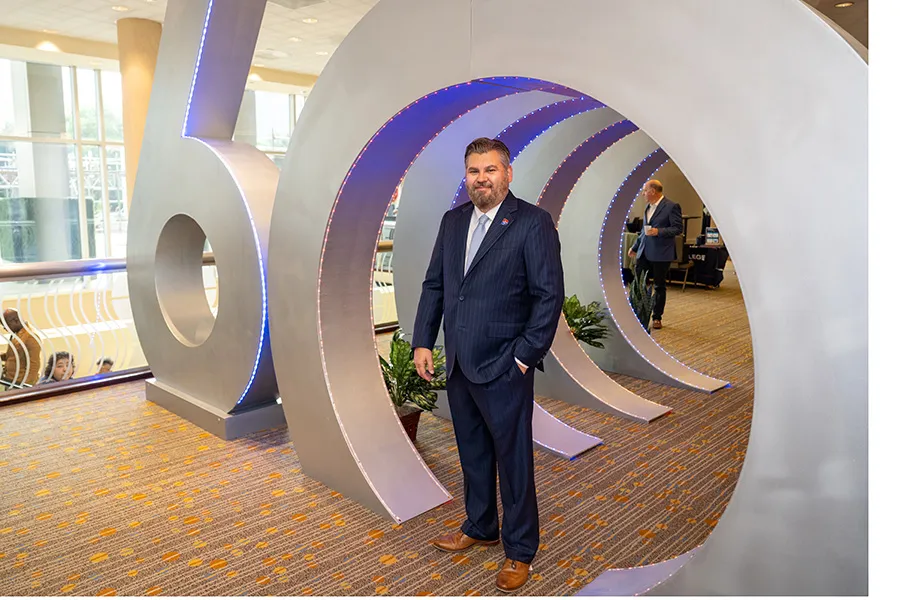 Dr. Justin Lonon, Dallas College Chancellor poses with 60th Anniversary sculpture.