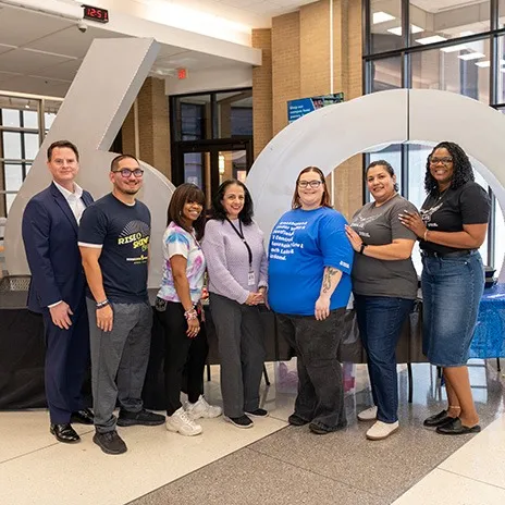Students at El Centro pose for a photo in front of the 60th Anniversary sculpture with the campus president
