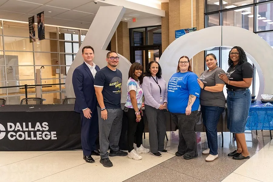 Students at El Centro pose for a photo in front of the 60th Anniversary sculpture with the campus president