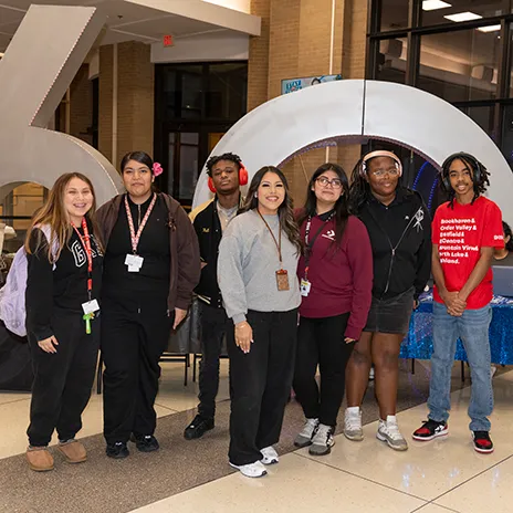 Group of seven students pose in front of 60th Anniversary sculpture.