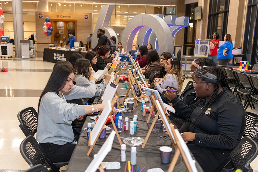 Students paint on easels with 60th Anniversary sculpture in background.