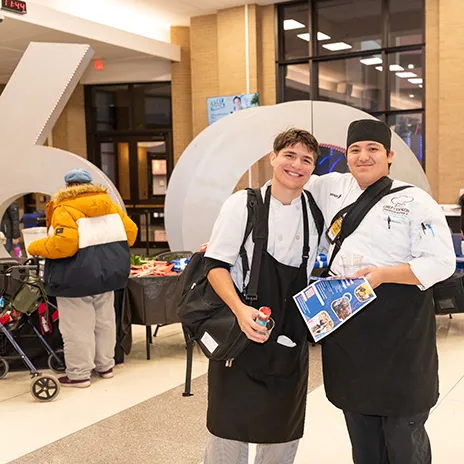 Two culinary students pose in front of 60th Anniversary sculpture.