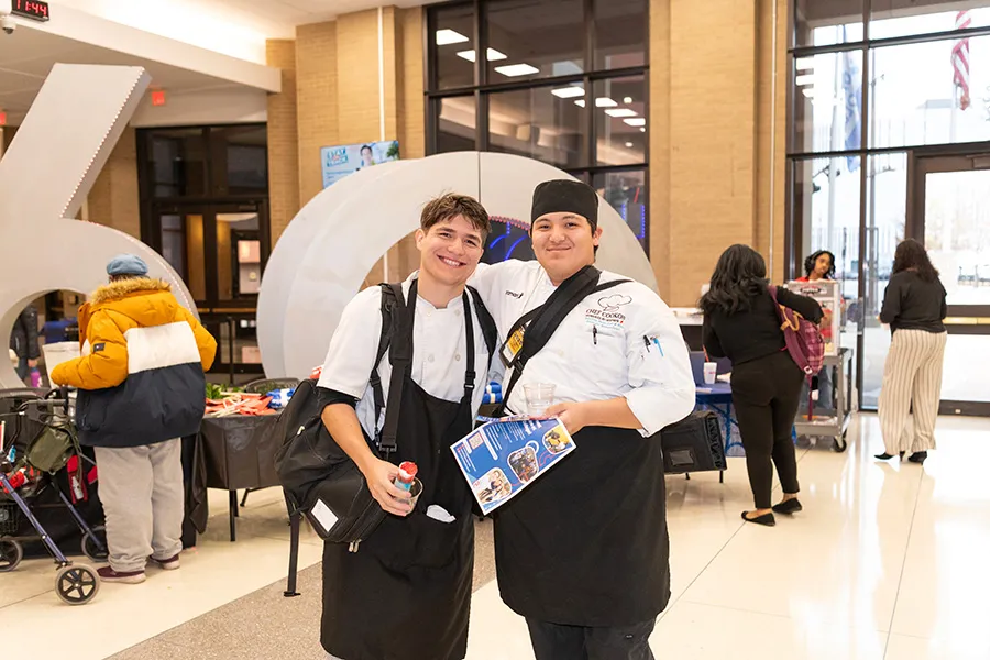 Two culinary students pose in front of 60th Anniversary sculpture.
