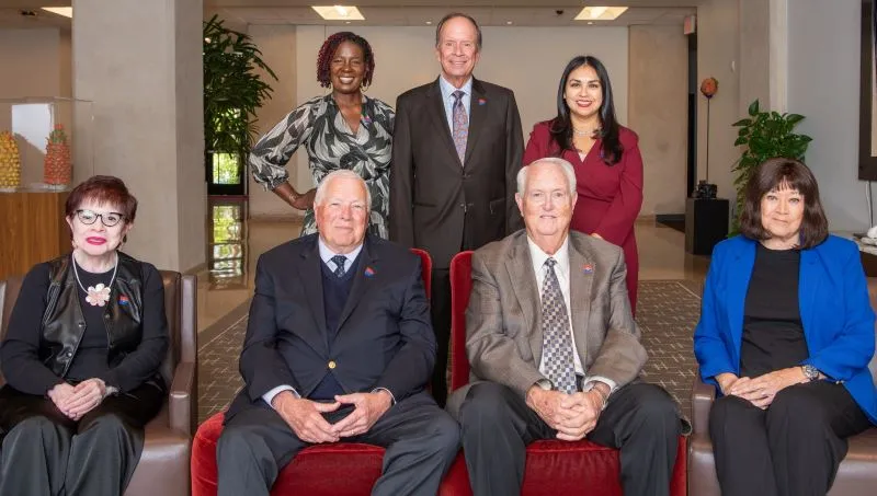 The 2025 Board of Trustees pose for a photo in the lobby of the admin building. loading=