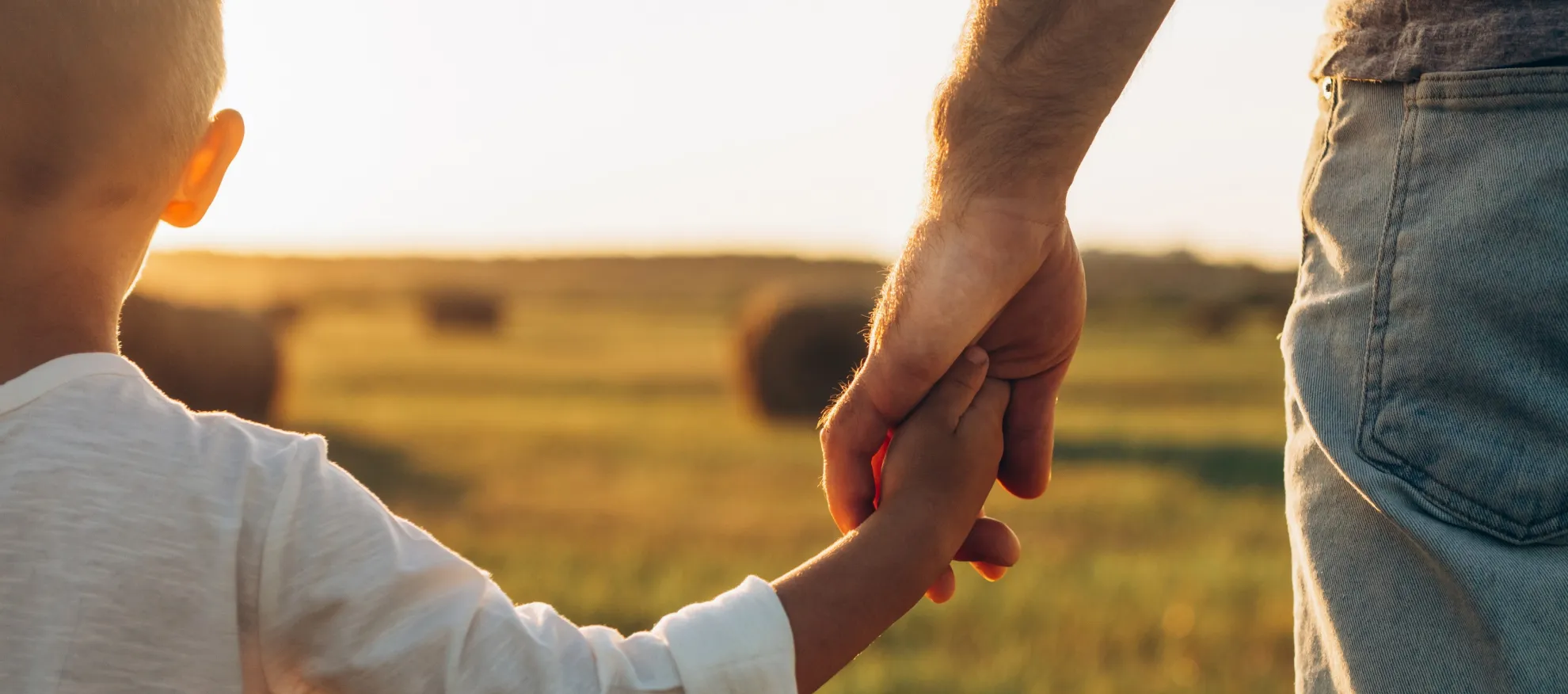 A child and parent holding hands while walking forward