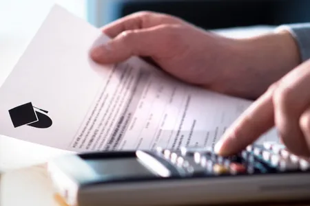 A student fills out form at a desk with a calculator nearby