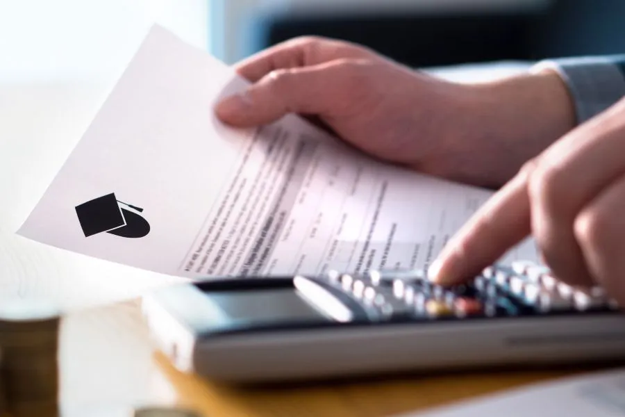 A student fills out form at a desk with a calculator nearby