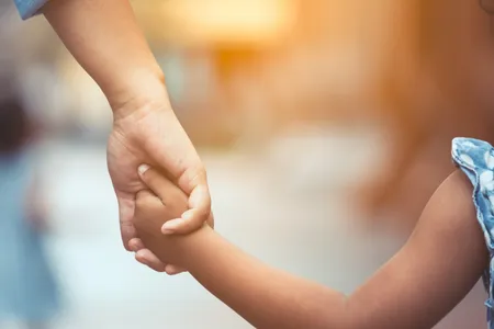 A daughter holds her father's hand