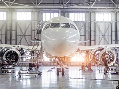 Commercial aircraft undergoing maintenance inside an aircraft hangar.