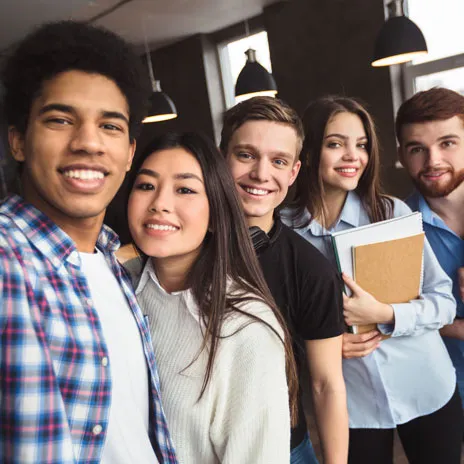 group of smiling students standing inside a room