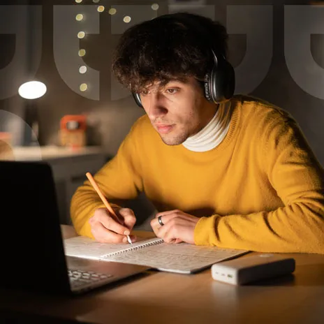 Boy wearing earphone doing homework on a computer