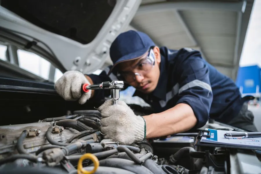 An automotive technician uses a ratchet wrench to tighten a bolt on a car engine.