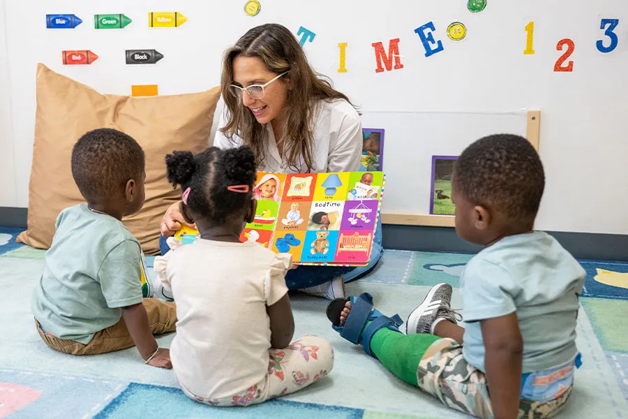 Teacher sitting holding a book with children
