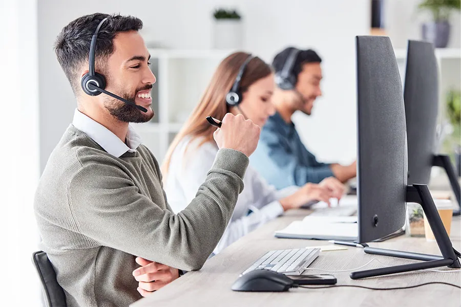 Call center representative with headset smiling at a computer