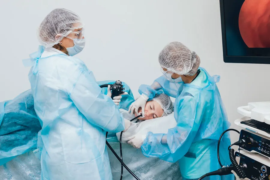 two endoscopy technicians perform procedure on patient lying down