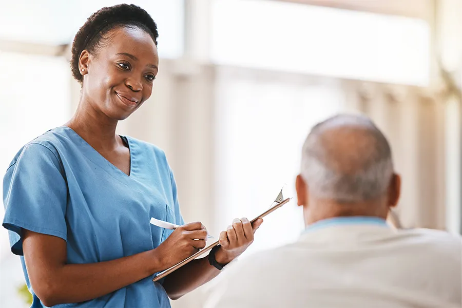 Medical assistant smiling and taking notes with patient