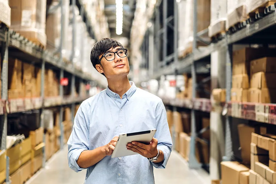 Man with checking rows of products in a warehouse