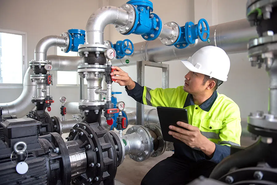 Plumber inspects pressure valve on a system of pipes