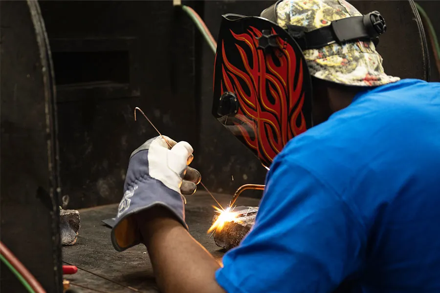 Welder soldering metal at a workstation