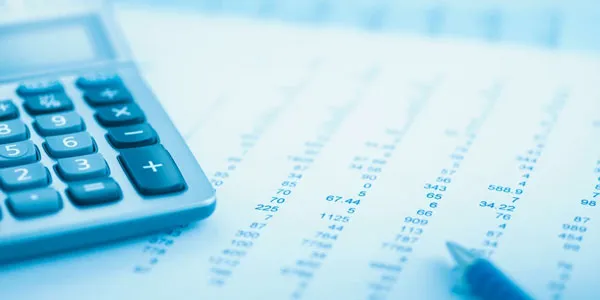 Calculator and financial documents with printed numbers on a desk.
