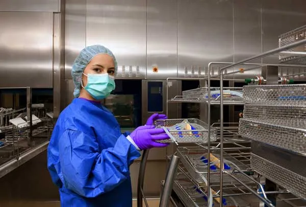 female in mask gloves hairnet and protective wear at a metal tray