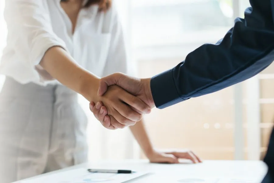 Two people shake hands across a table