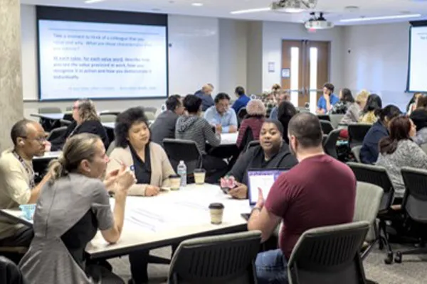 Dallas College employees sit around tables as they take part in a convening session