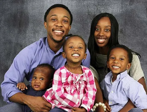 Family of five posing for a portrait; two adults and three children in casual clothing.