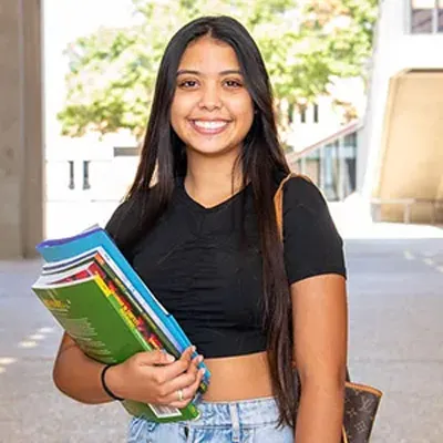 female smiling holding books and smiling