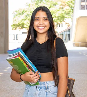 female smiling holding books and smiling