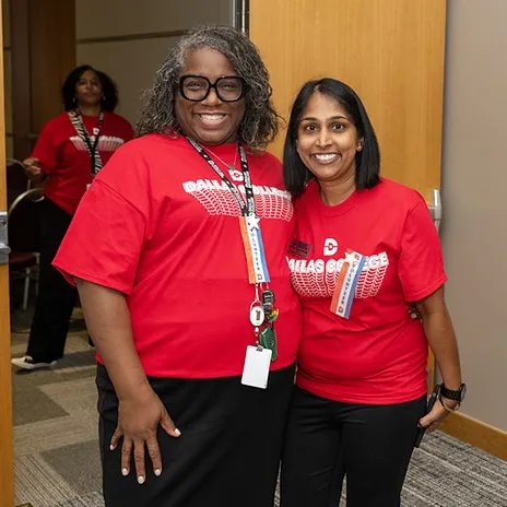 Employees pose for a photo at Conference Day wearing red Dallas College shirts.