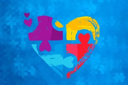graphic of a heart with multicolored puzzle pieces in it on a blue background