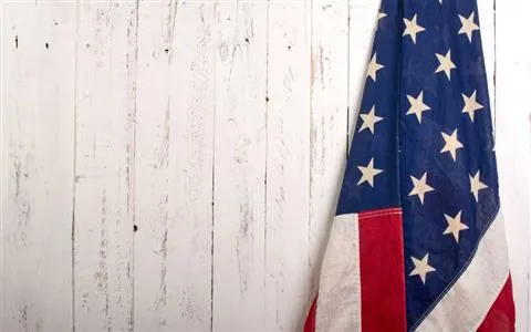 American flag wrapped around its pole against a white all