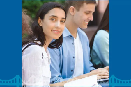 a row of students sitting outside, working on laptops or notebooks