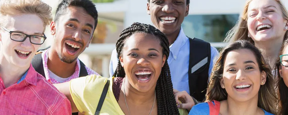 Group of students standing closely together outdoors, posing for a photo.