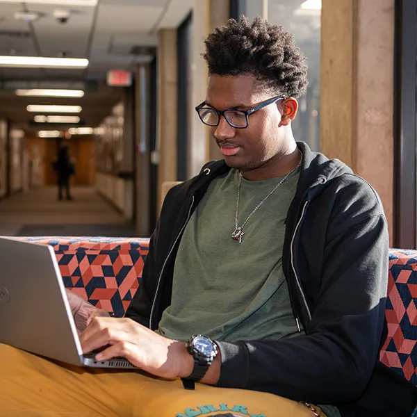 male student sitting at desk with laptop