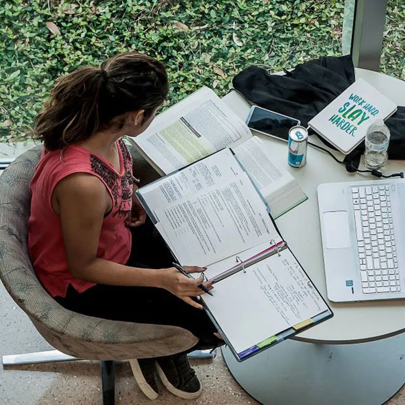 Looking down at a student sitting at table with books spread out, studying.