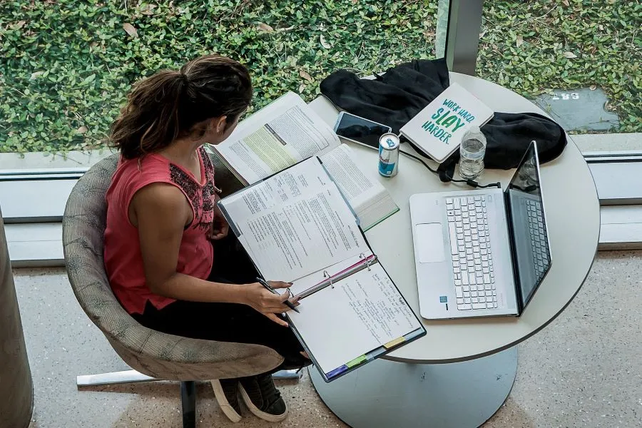 Looking down at a student sitting at table with books spread out, studying.