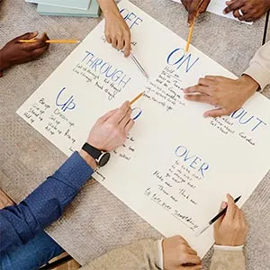 People gather around a large poster and pointed out various English phrases