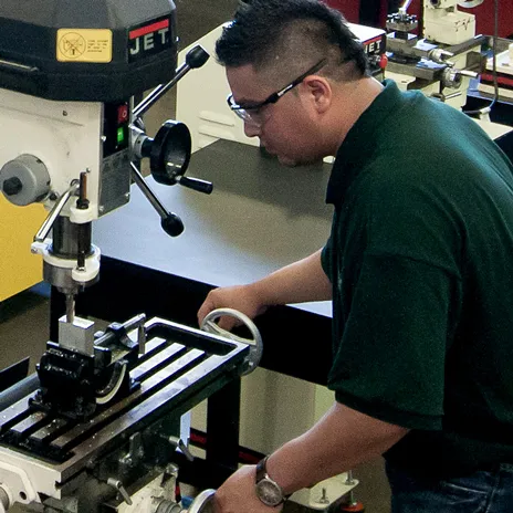 A student works on a drill press at the Garland Center