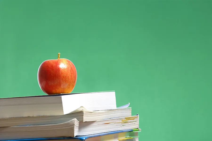 A red apple sitting on top of text books