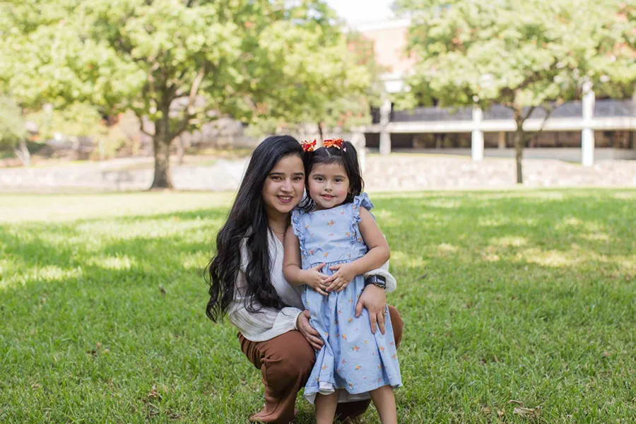Emily De La Rosa in front of a campus building with her daughter.