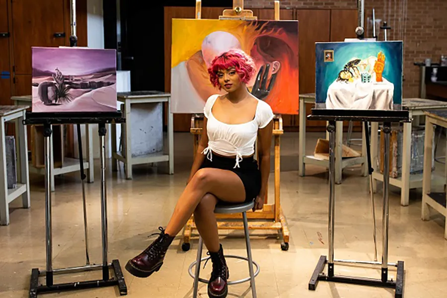 Arianna Castillo sitting in a studio surrounded by her artwork.