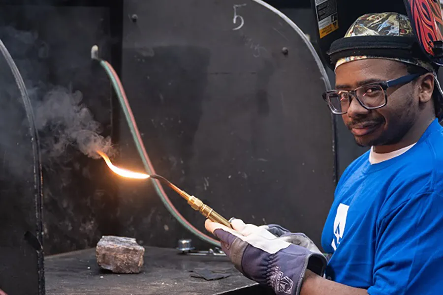 Caleb Lynn holding welding torch.
