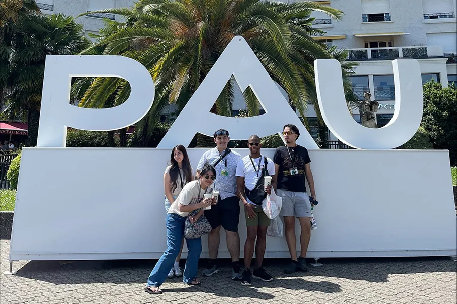 Five students posting in front of the letters PAU.