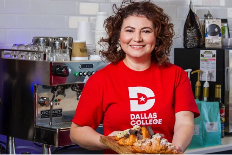 Sayada Rapalo wearing a red Dallas College shirt while showing pastries on a cutting board in the kitchen.