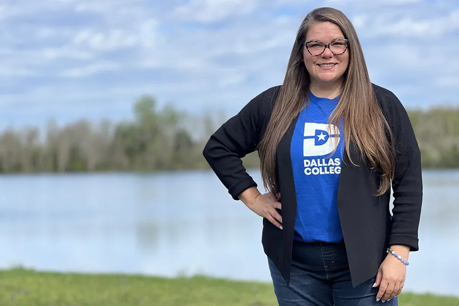 Dr. Meagan Pollock stands in front a body of water with her hand on her hip.