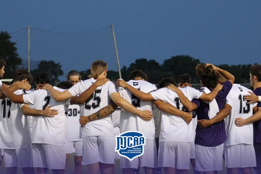 Group of soccer players huddle on the field.